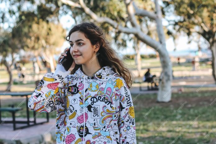 cute-young-teenager-girl-talking-with-friends-by-phone-pretty-teen-outside-trees_72594-2290